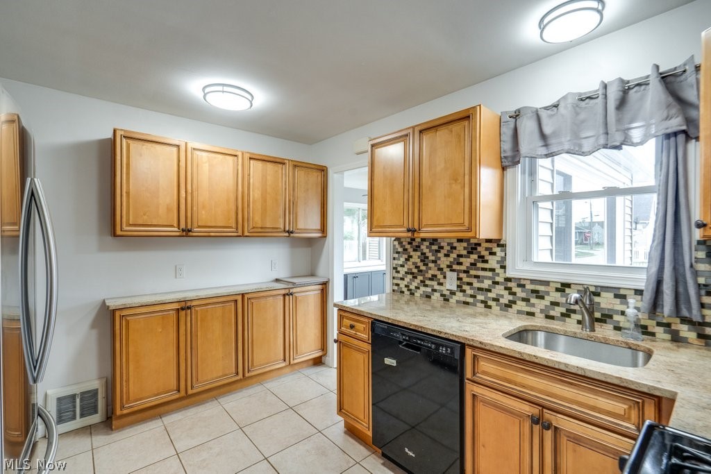 30000 Elgin Road Wickliffe, OH 44092 - Photo 4 of 30 Kitchen featuring wood cabinetry, stone countertops, a stainless steel sink with a gooseneck faucet, a tile backsplash, and tile flooring