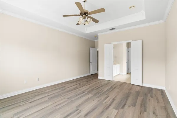 an empty room with wooden floor and a ceiling fan