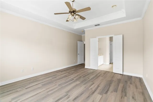 an empty room with wooden floor and a ceiling fan