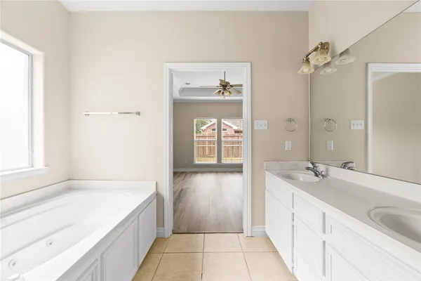 a spacious bathroom with a tub sink and mirror