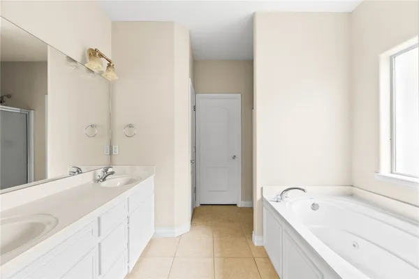 a spacious bathroom with a tub sink and mirror