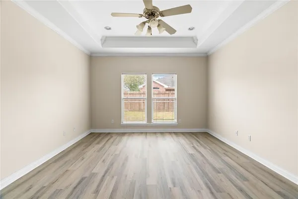 an empty room with wooden floor chandelier fan and windows
