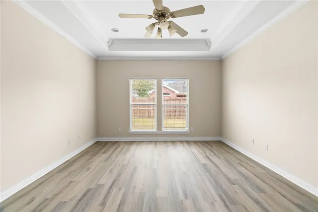 an empty room with wooden floor chandelier fan and windows
