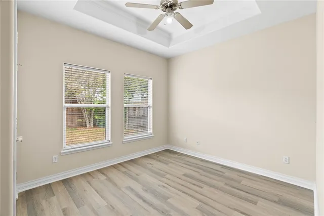 an empty room with wooden floor fan and windows