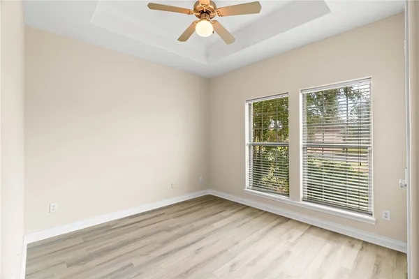 an empty room with wooden floor fan and windows