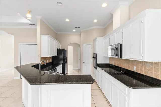 a kitchen with granite countertop a sink a stove and refrigerator