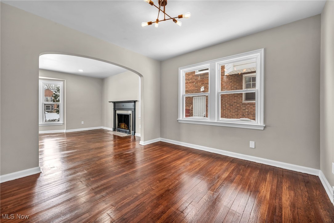 13614 Cedar Road Cleveland, OH 44118 - Photo 8 of 46 Unfurnished living room featuring dark wood-style floors, a chandelier, baseboards, and a fireplace with flush hearth
