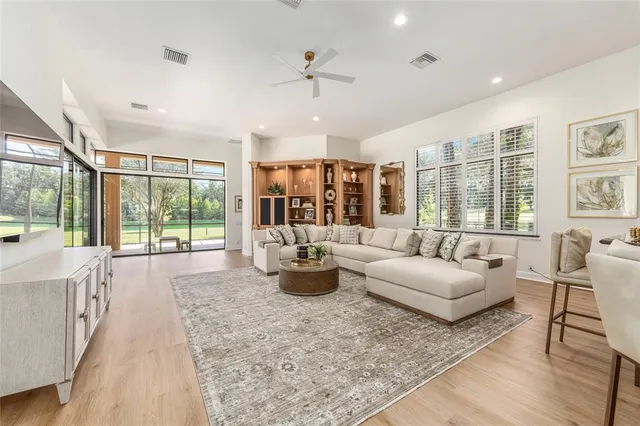 a kitchen with stainless steel appliances kitchen island granite countertop a refrigerator a stove a sink a dining table and chairs with wooden floor