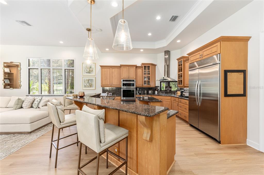 708 Southeast 44th Road Ocala, FL 34480 - Photo 23 of 76 a kitchen with stainless steel appliances kitchen island granite countertop a refrigerator a stove a sink a dining table and chairs with wooden floor