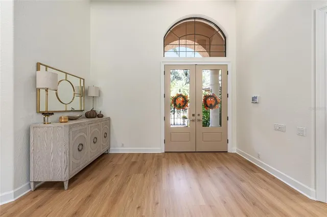 an empty room with wooden floor mirror and windows