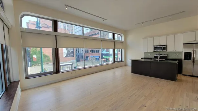 a large kitchen with stainless steel appliances a large window a oven a counter space and a window