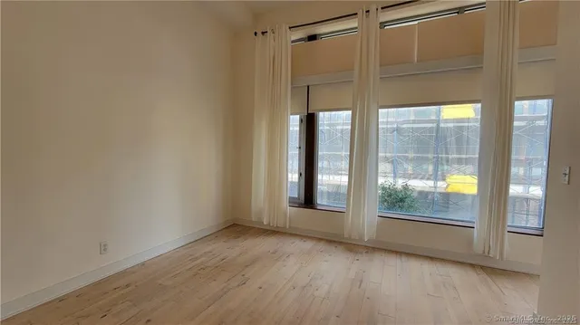 a view of empty room with wooden floor and fan
