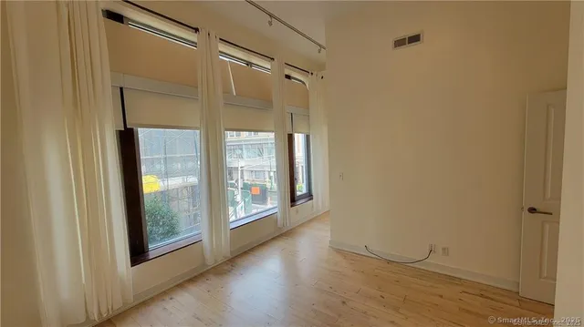 a view of a big room with wooden floor and windows