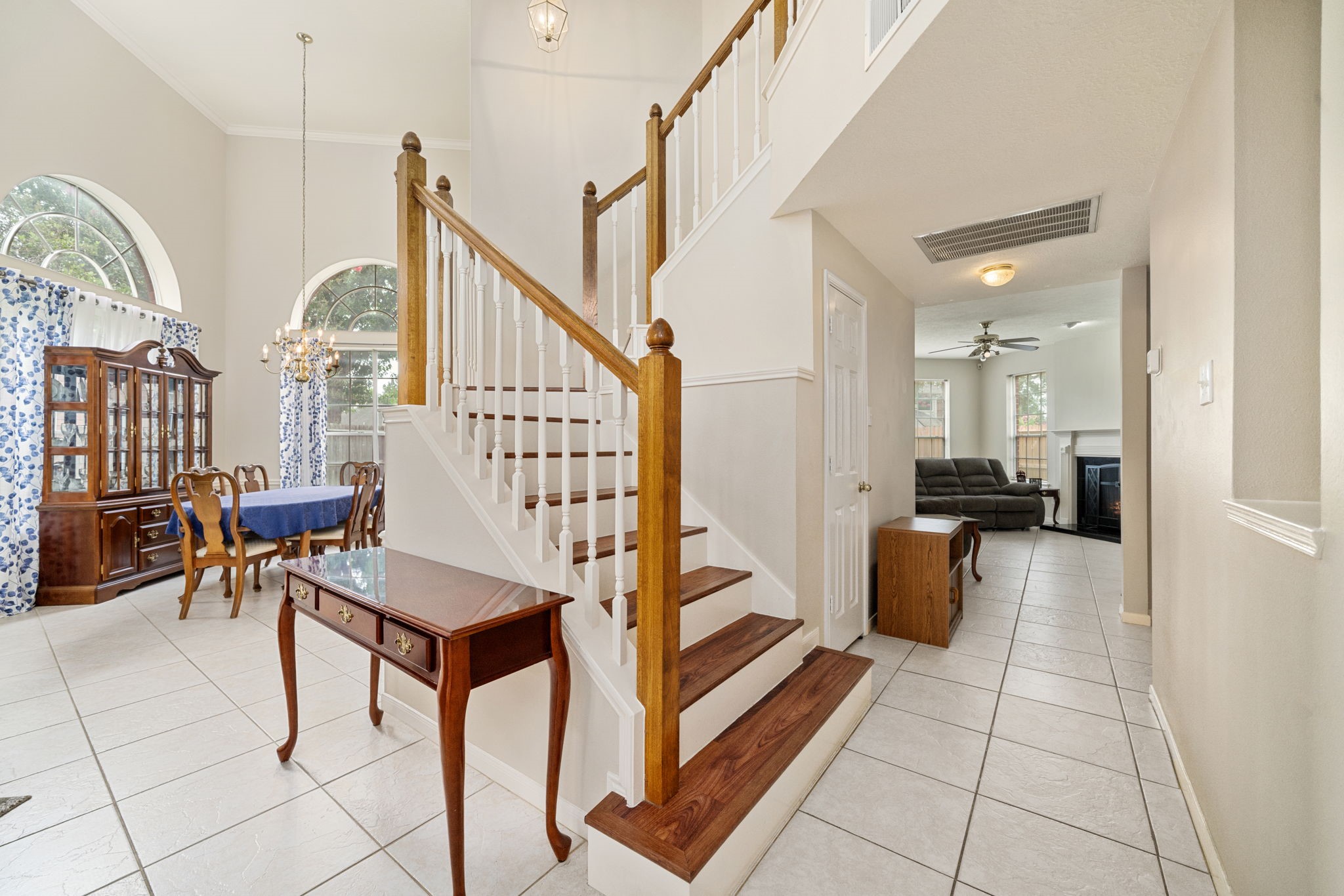 9715 Therrell Drive Houston, TX 77064 - Photo 17 of 33 Foyer featuring soaring ceilings, classic wood staircase with white spindle railing, and open sightlines to both the formal dining room and family room.