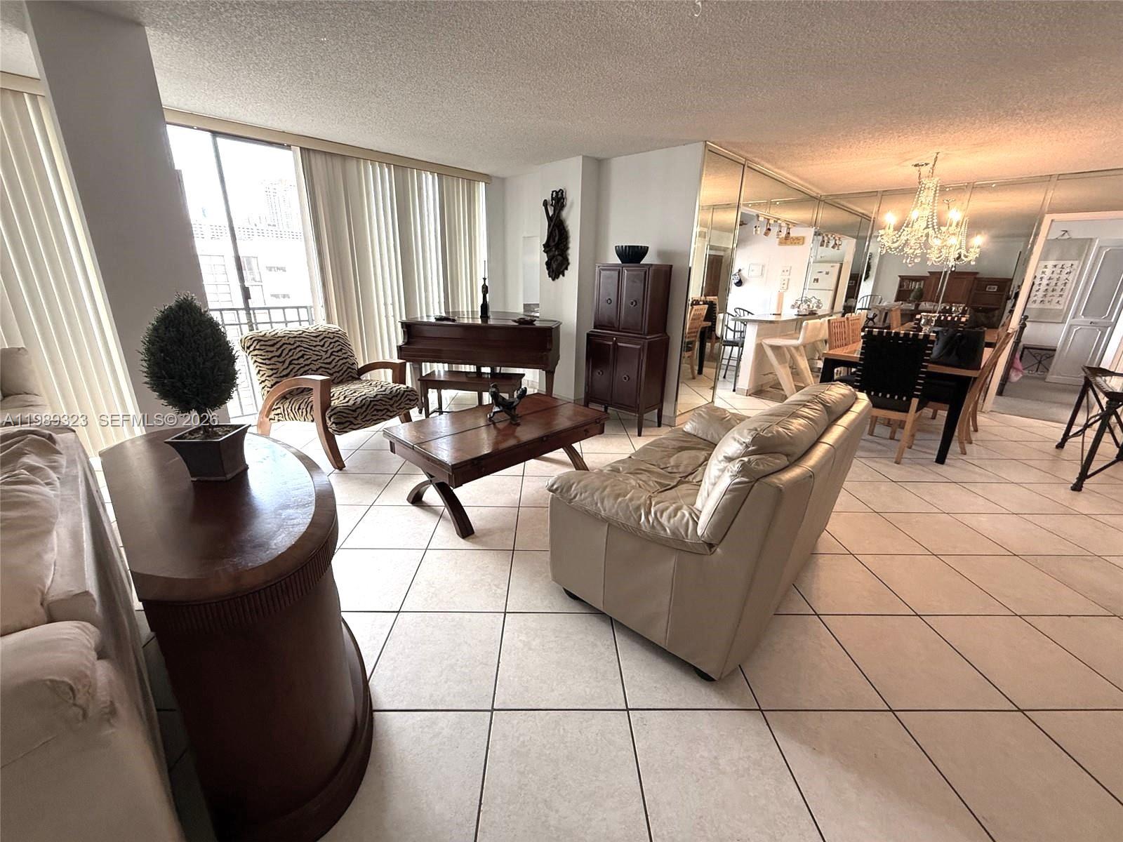 17011 North Bay Road, Unit 1007 Sunny Isles Beach, FL 33160 - Photo 5 of 28 a living room with couches and a dining table with kitchen view