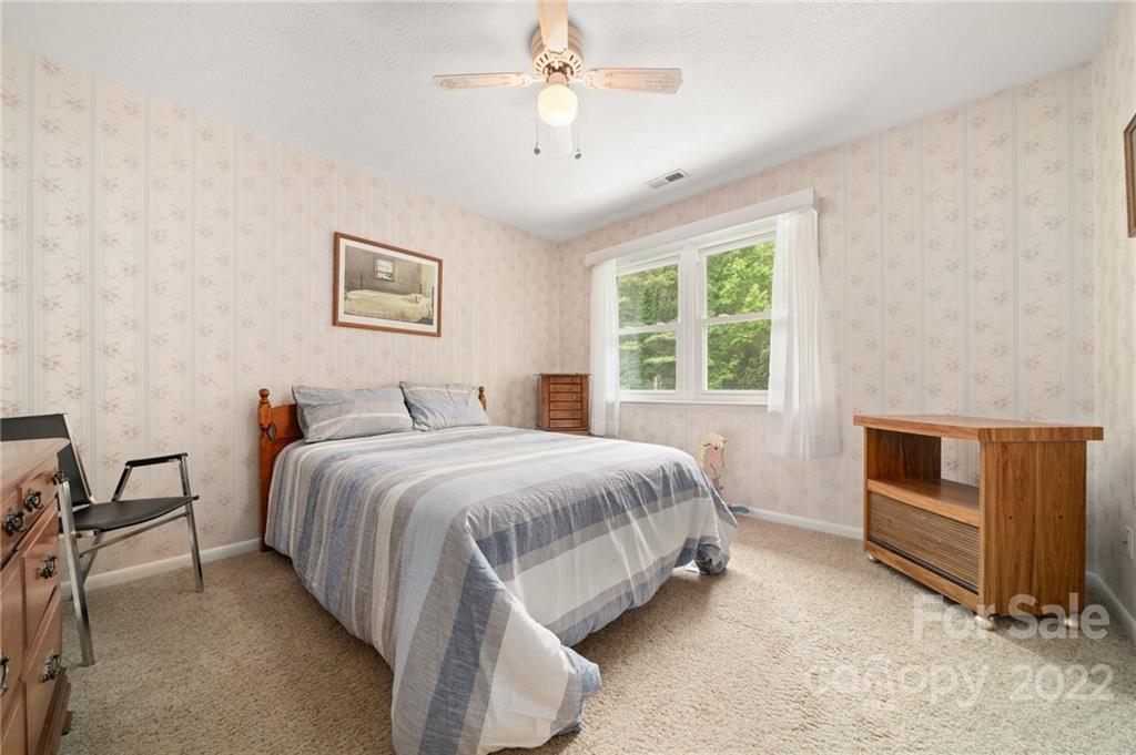2480 Ridge Road Hendersonville, NC 28792 - Photo 31 of 48 a spacious bedroom with a bed and a chandelier