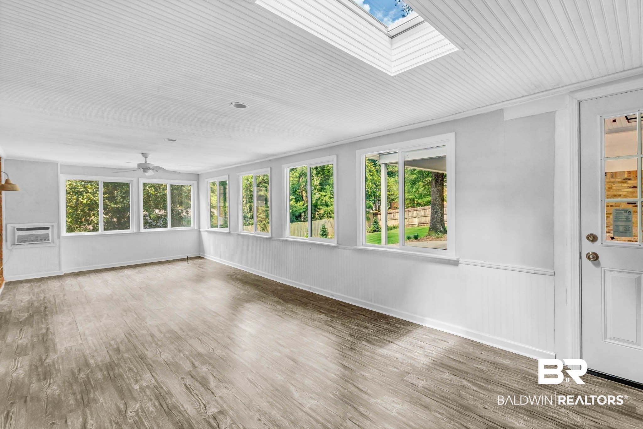 309 West Brandy Run Road Mobile, AL 36608 - Photo 72 of 100 Unfurnished sunroom featuring wood finished floors, plenty of natural light, a skylight, a wainscoted wall, and an AC wall unit