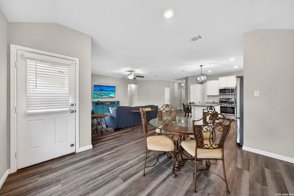 a kitchen with stainless steel appliances granite countertop a stove top oven a refrigerator a sink dishwasher a dining table and chairs with wooden floor
