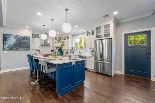 a kitchen with stainless steel appliances kitchen island granite countertop a refrigerator a stove a sink dishwasher a dining table and chairs with wooden floor