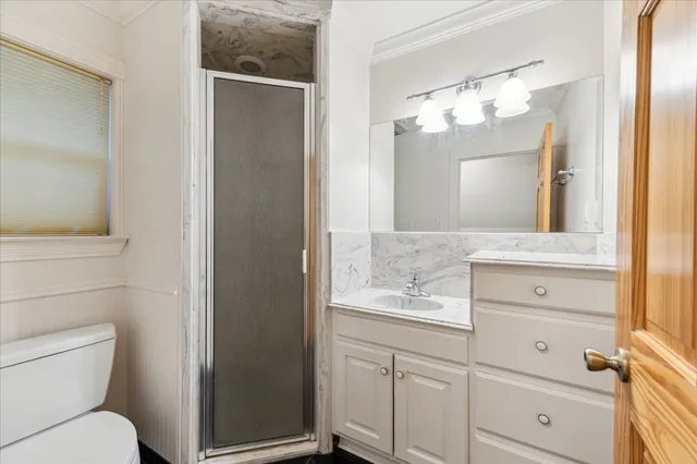 a bathroom with a granite countertop sink vanity mirror and toilet
