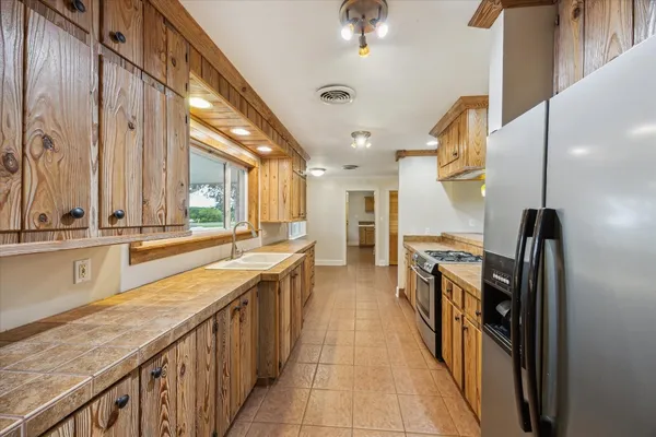 a view of a kitchen with stainless steel appliances granite countertop a sink a counter space and a window
