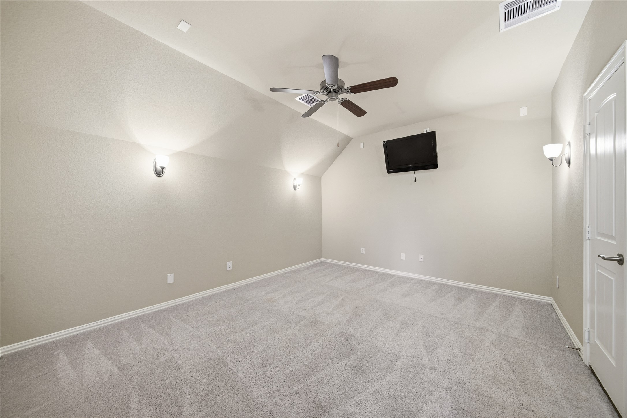 5303 Mesquite Willow Lane Rosharon, TX 77583 - Photo 25 of 32 This media room is spacious with neutral walls and carpet, featuring a ceiling fan and soft lighting from wall fixtures.