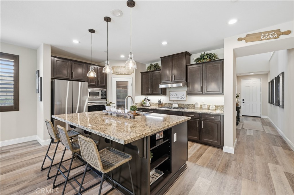 24903 Shadow Ridge Court Valencia, CA 91354 - Photo 14 of 43 a kitchen with stainless steel appliances granite countertop a kitchen island hardwood floor and a sink