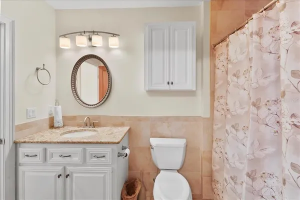 a bathroom with a granite countertop toilet a sink and a mirror