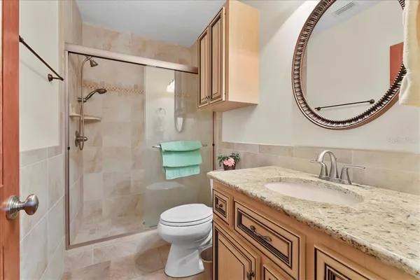 a bathroom with a granite countertop sink a toilet and a mirror