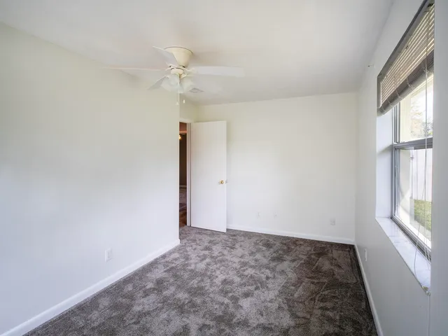 an empty room with an entryway and chandelier fan