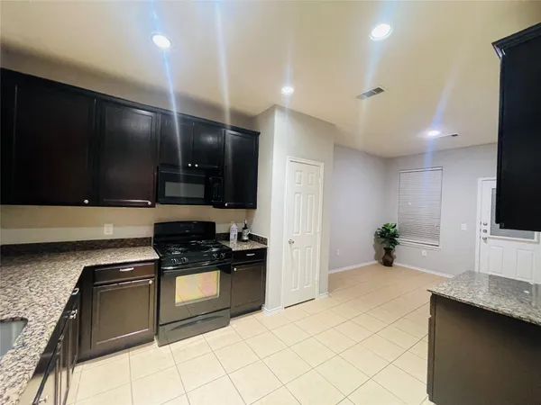 a kitchen with stainless steel appliances kitchen island granite countertop a stove a sink and a microwave