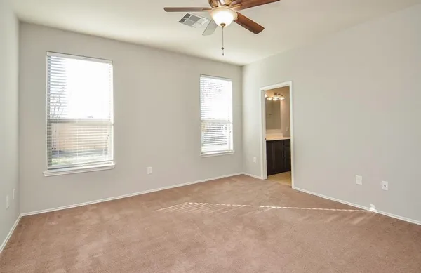 an empty room with chandelier fan and windows