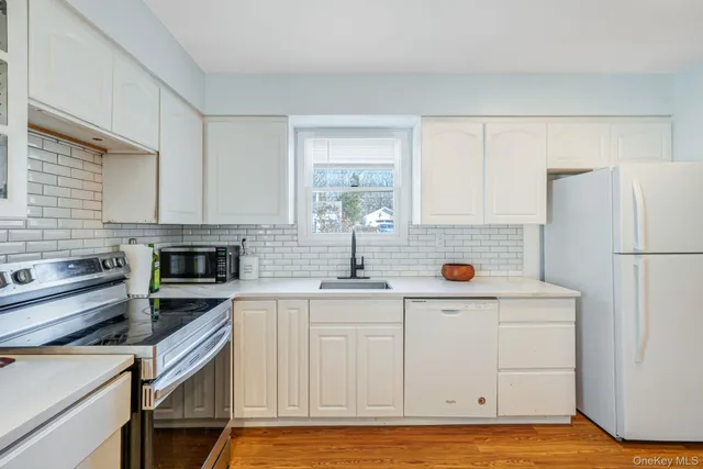 a kitchen with stainless steel appliances a stove a sink and white cabinets