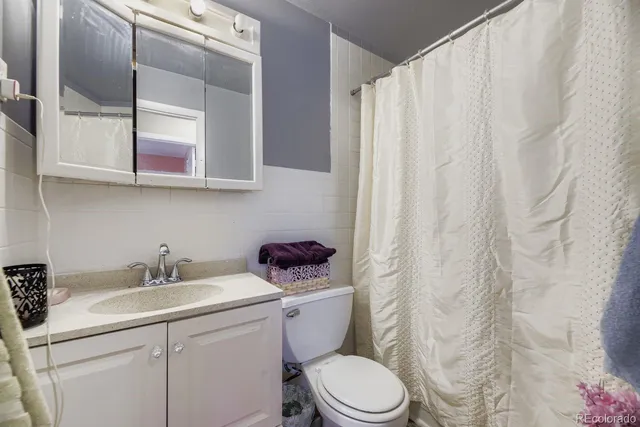 a bathroom with a sink a toilet and shower curtain