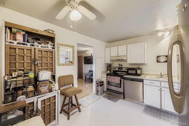 a kitchen with stainless steel appliances granite countertop a stove top oven a sink a dining table and chairs with wooden floor