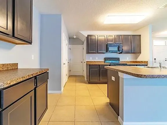 a kitchen with stainless steel appliances granite countertop a stove a sink and a microwave