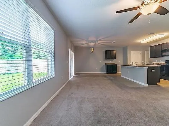a view of an empty room with a window and kitchen view