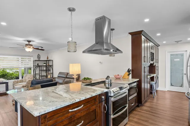 a kitchen with stainless steel appliances granite countertop a kitchen island a stove and a wooden floors