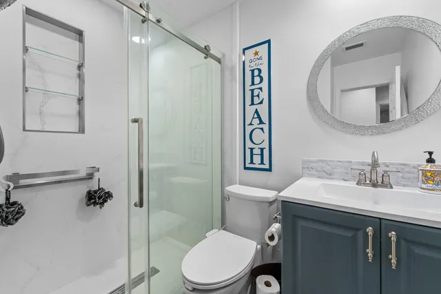 a bathroom with a toilet a sink a mirror a vanity and shower