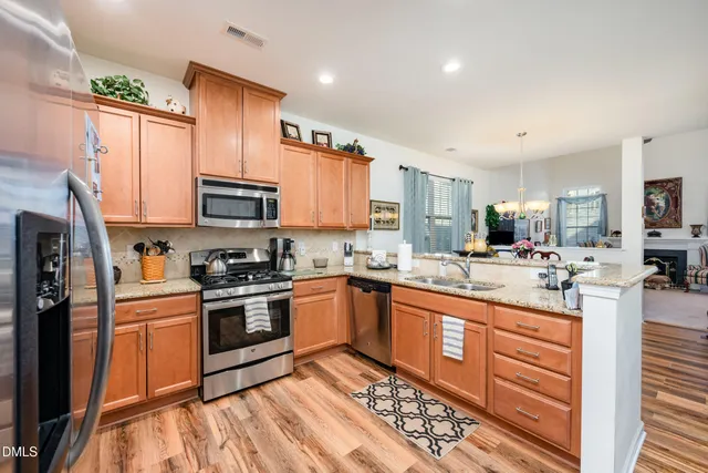 a kitchen with stainless steel appliances granite countertop a stove top oven a sink dishwasher a refrigerator and cabinets with wooden floor