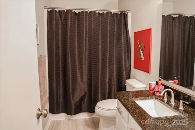 a bathroom with a granite countertop sink vanity mirror and toilet