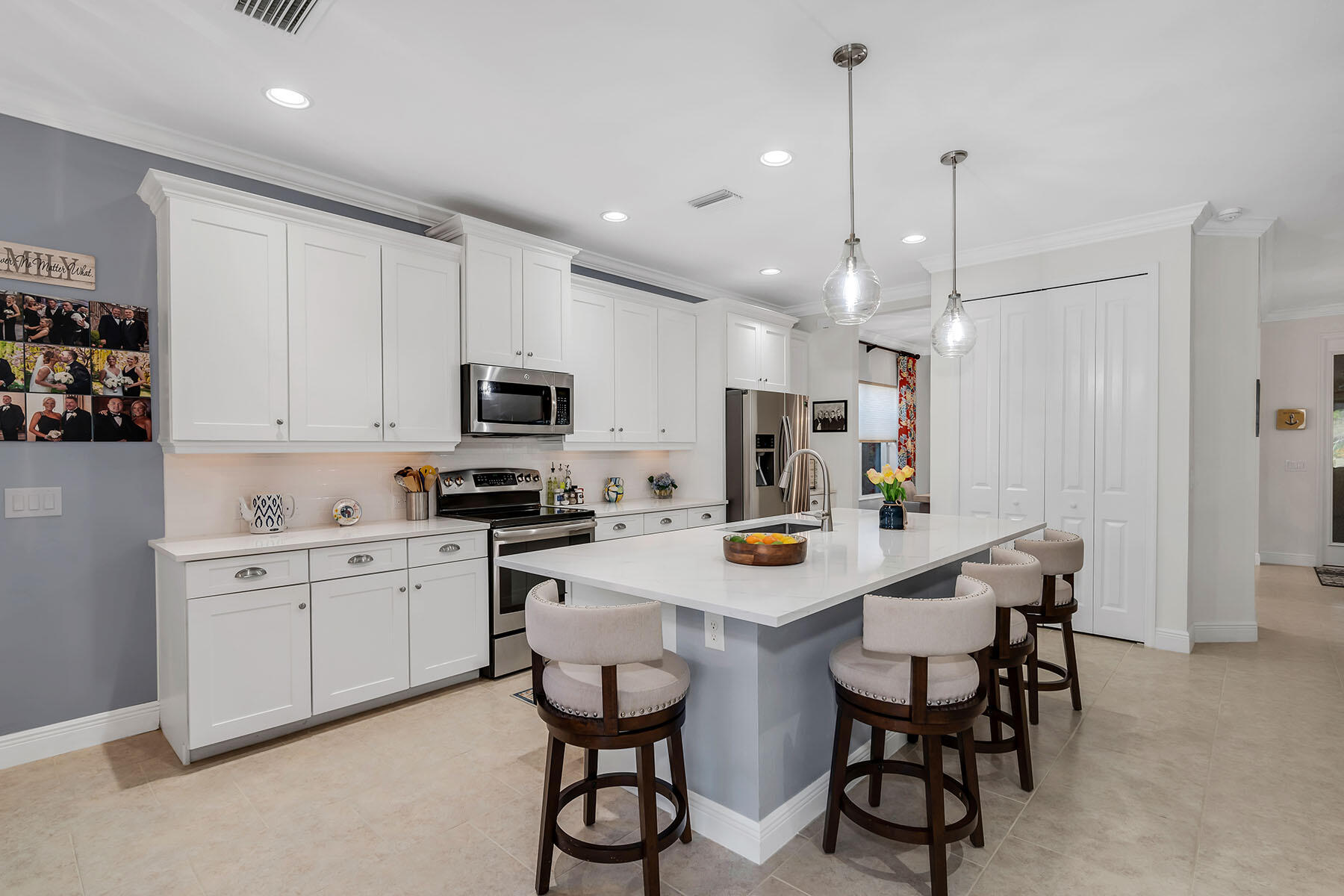 3783 Canopy Circle Naples, FL 34120 - Photo 5 of 39 a kitchen with kitchen island white cabinets and stainless steel appliances
