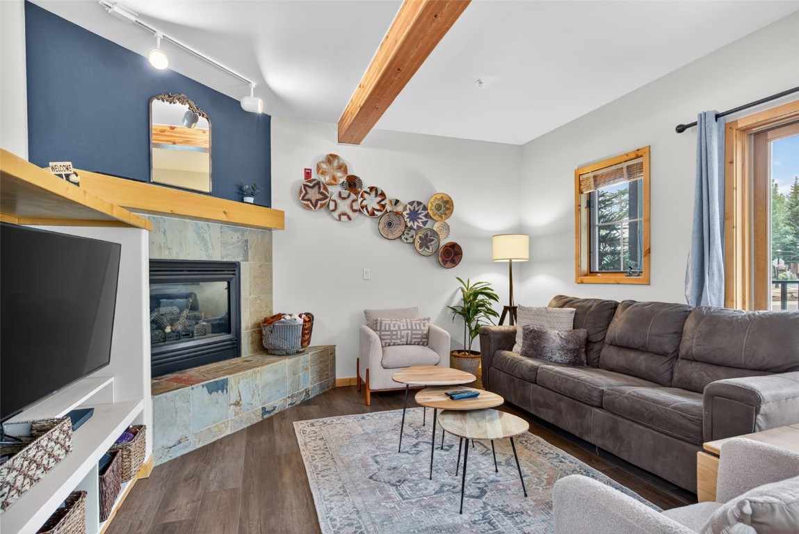 260 Ski Hill Road, Unit 6 Breckenridge, CO 80424 - Photo 24 of 25 Living area featuring beamed ceiling, a tile fireplace, track lighting, and wood finished floors
