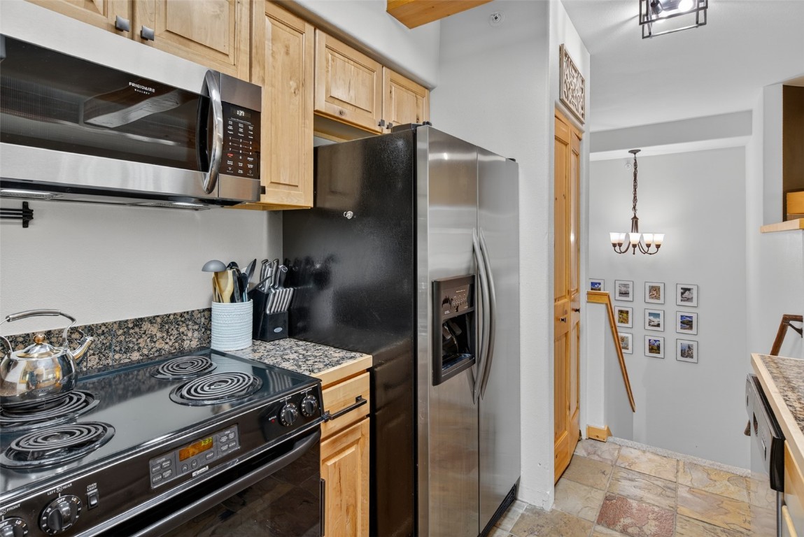 260 Ski Hill Road, Unit 6 Breckenridge, CO 80424 - Photo 9 of 25 Kitchen featuring appliances with stainless steel finishes, stone tile flooring, a chandelier, and light brown cabinetry