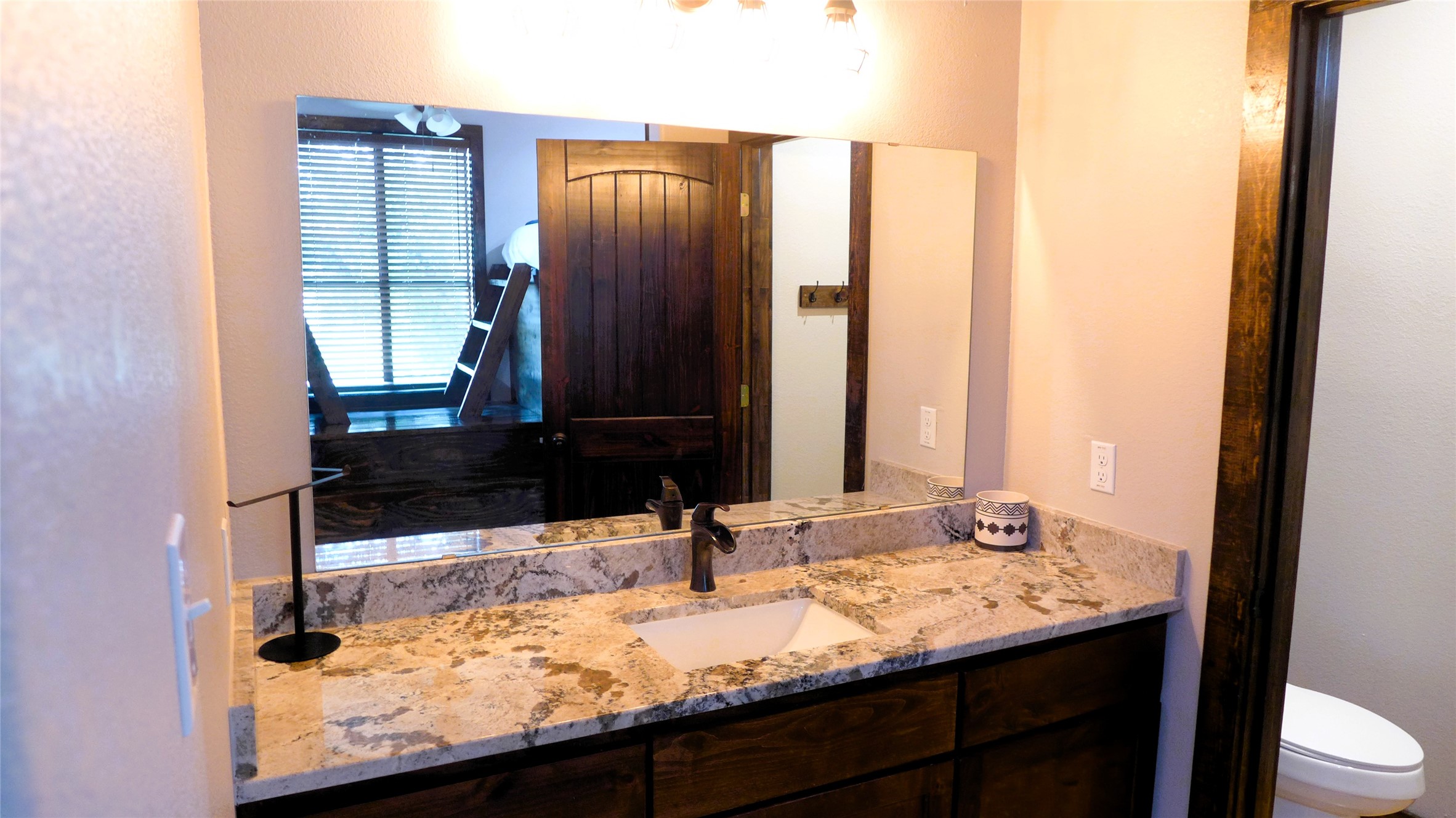 1718 Mountain Valley Road Concan, TX 78838 - Photo 25 of 40 Rich wood cabinetry pairs with elegant stone countertops in this refined restroom space.