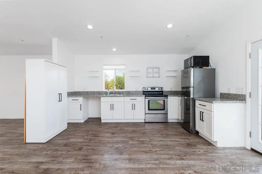 6778 West Lilac Road Bonsall, CA 92003 - Photo 23 of 45 a kitchen with granite countertop a refrigerator stove top oven and sink