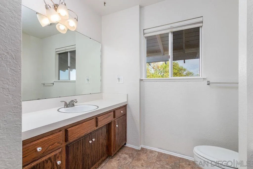 6778 West Lilac Road Bonsall, CA 92003 - Photo 33 of 45 a bathroom with a toilet sink and mirror