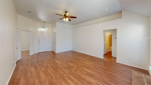 a view of empty room with wooden floor and ceiling fan