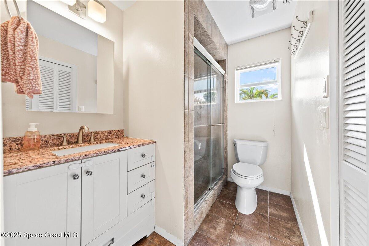 985 Sycamore Drive Rockledge, FL 32955 - Photo 17 of 26 a bathroom with a granite countertop sink toilet a mirror and a shower