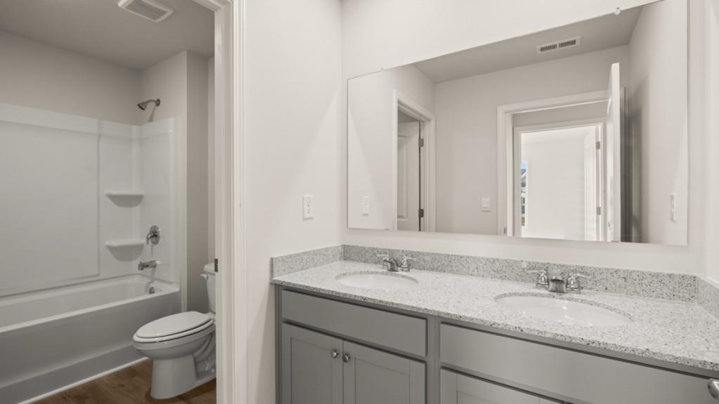 703 Anchor Avenue Villa Rica, GA 30180 - Photo 30 of 32 a bathroom with a granite countertop toilet sink and mirror a bathtub